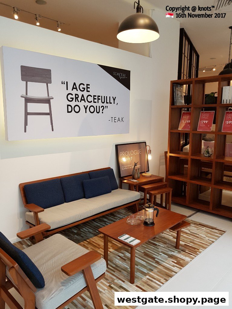 An interior shot of Scanteak Signature showroom featuring wooden furniture and a promotional sign.