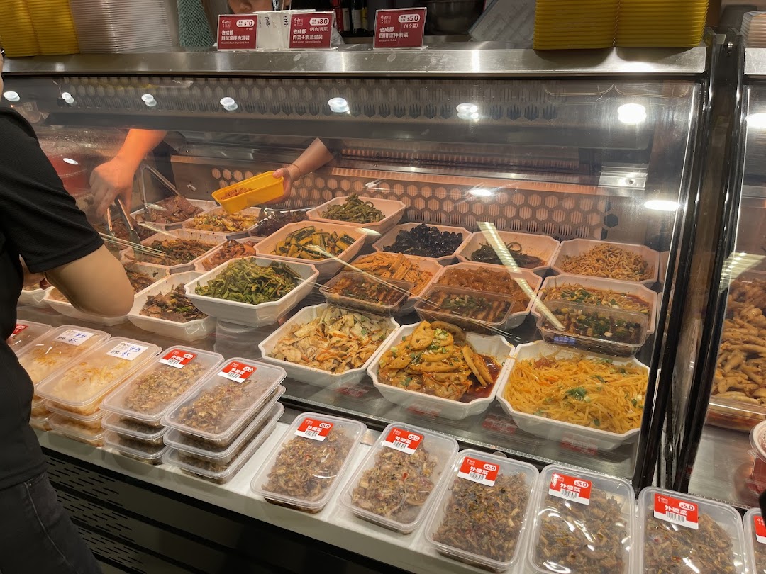 A vibrant display of various freshly prepared Asian dishes and snacks in a supermarket deli counter.
