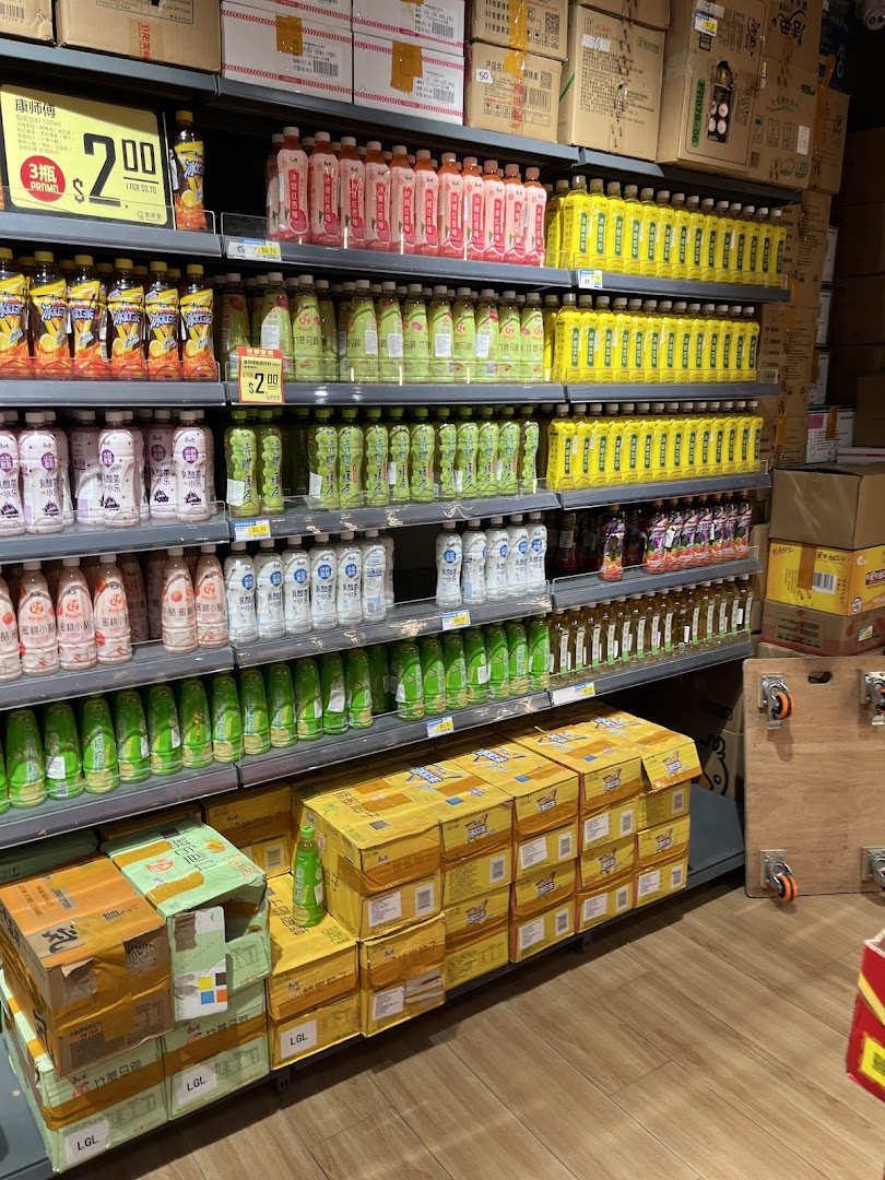 A well-stocked supermarket aisle displaying a wide variety of bottled beverages and stacked product boxes.