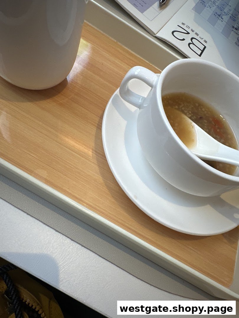 A close-up of a comforting meal on a tray, featuring a bowl of soup or congee and a cup.
