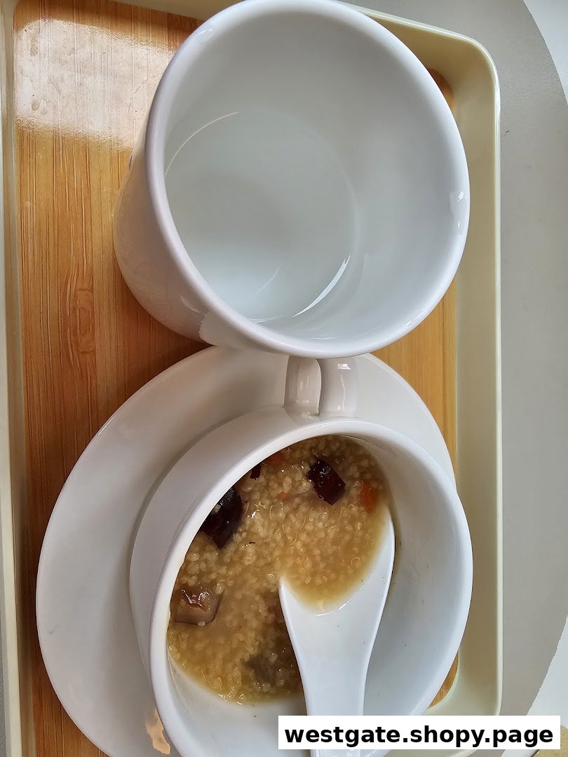 A bowl of wholesome porridge with a spoon and an empty cup, served on a wooden tray.