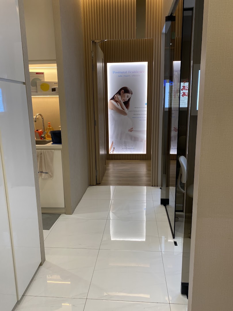 A bright, modern hallway with a 'Postnatal Healthcare' display leading to a treatment area.