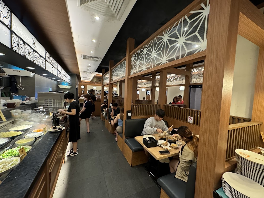 Diners enjoy hotpot at Shabu Sai, featuring a fresh ingredient bar and cozy wooden booths.
