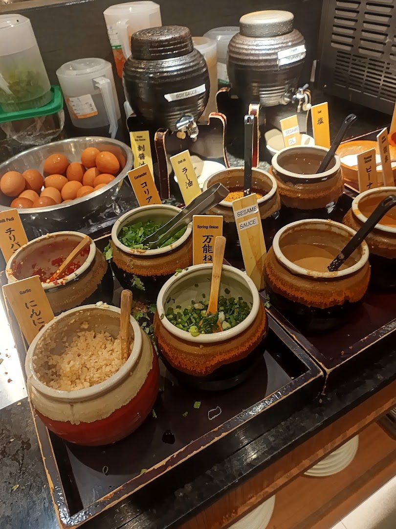 A vibrant self-serve sauce and condiment bar with fresh ingredients like garlic, spring onion, and eggs.