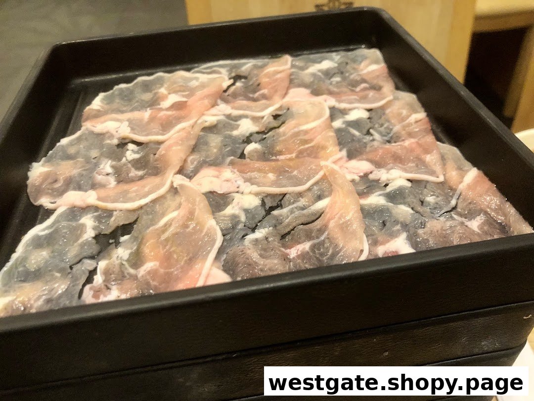 A black tray filled with thinly sliced raw meat, likely pork or beef, ready for shabu-shabu.