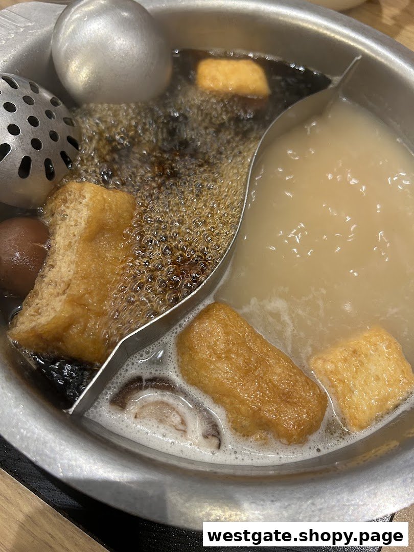 A close-up of a bubbling hot pot with two distinct broths and various ingredients.