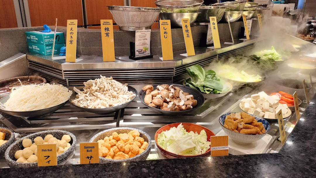 A hot pot buffet featuring fresh vegetables, mushrooms, and various ingredients.