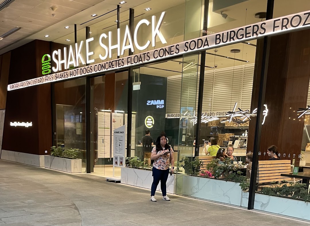 The illuminated storefront of Shake Shack, showcasing its entrance and product offerings.