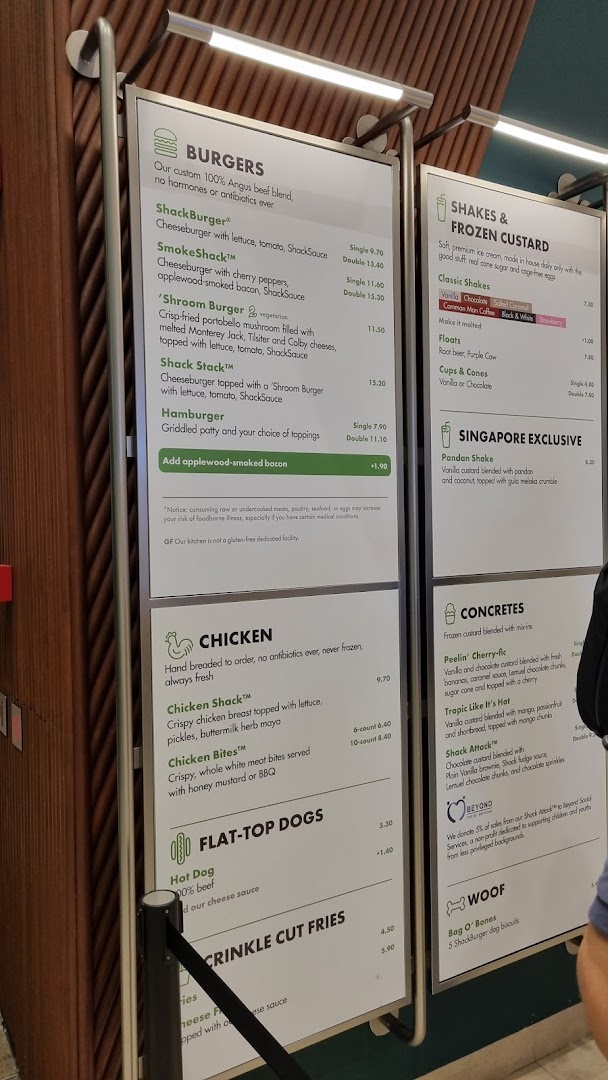 A detailed menu board displaying burgers, shakes, chicken, hot dogs, fries, and concretes at Shake Shack.