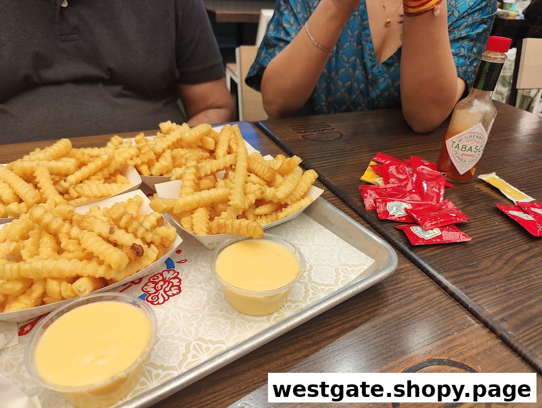Close-up of Shake Shack's signature crinkle-cut fries with cheese sauce and condiments on a wooden table.