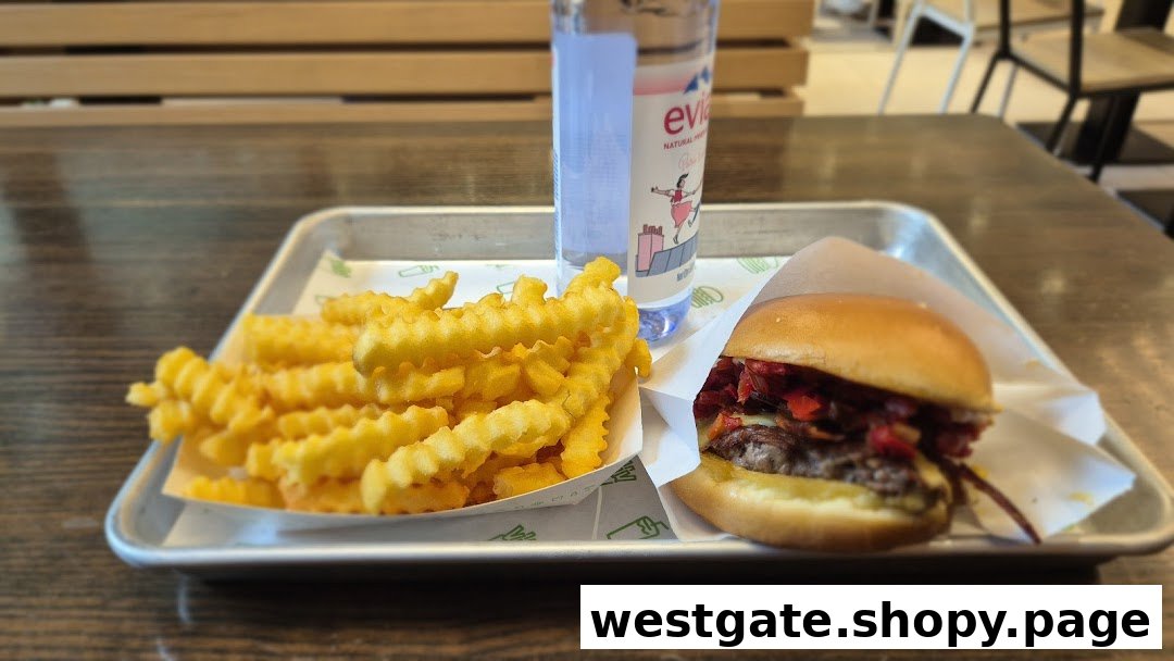 A tray featuring a Shake Shack burger, crinkle-cut fries, and an Evian water bottle.