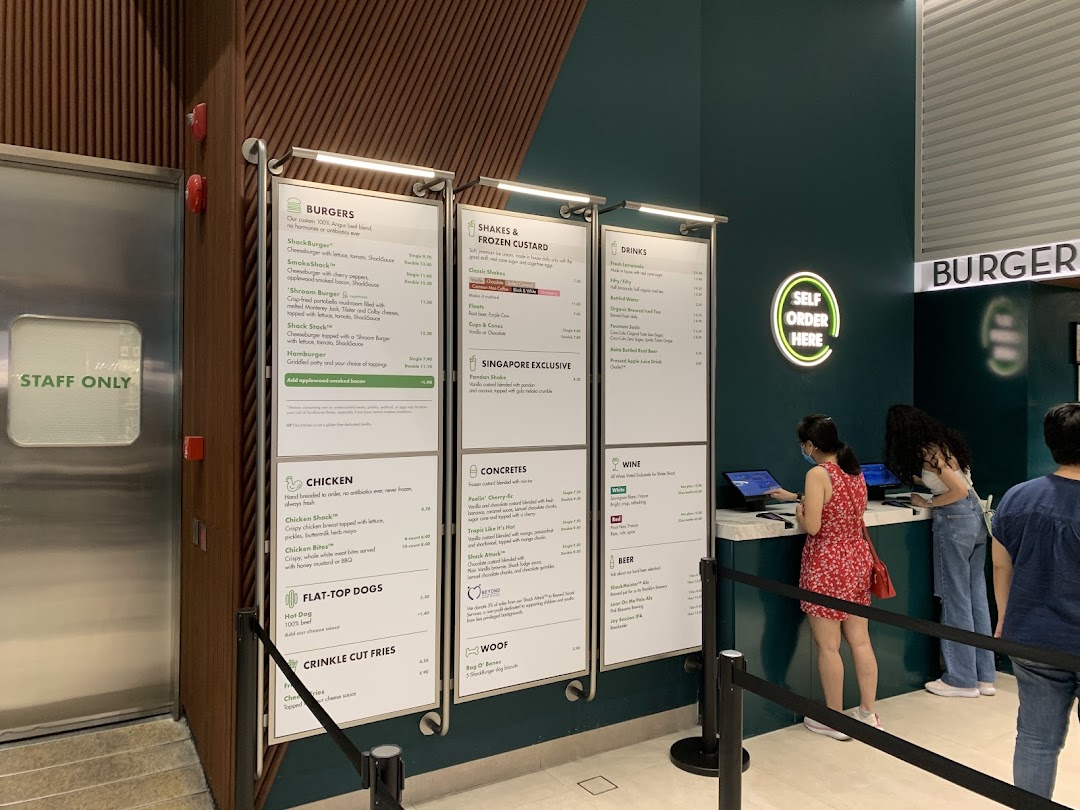 Digital menu boards and self-order kiosks at Shake Shack, showcasing their full range of burgers, shakes, and more.