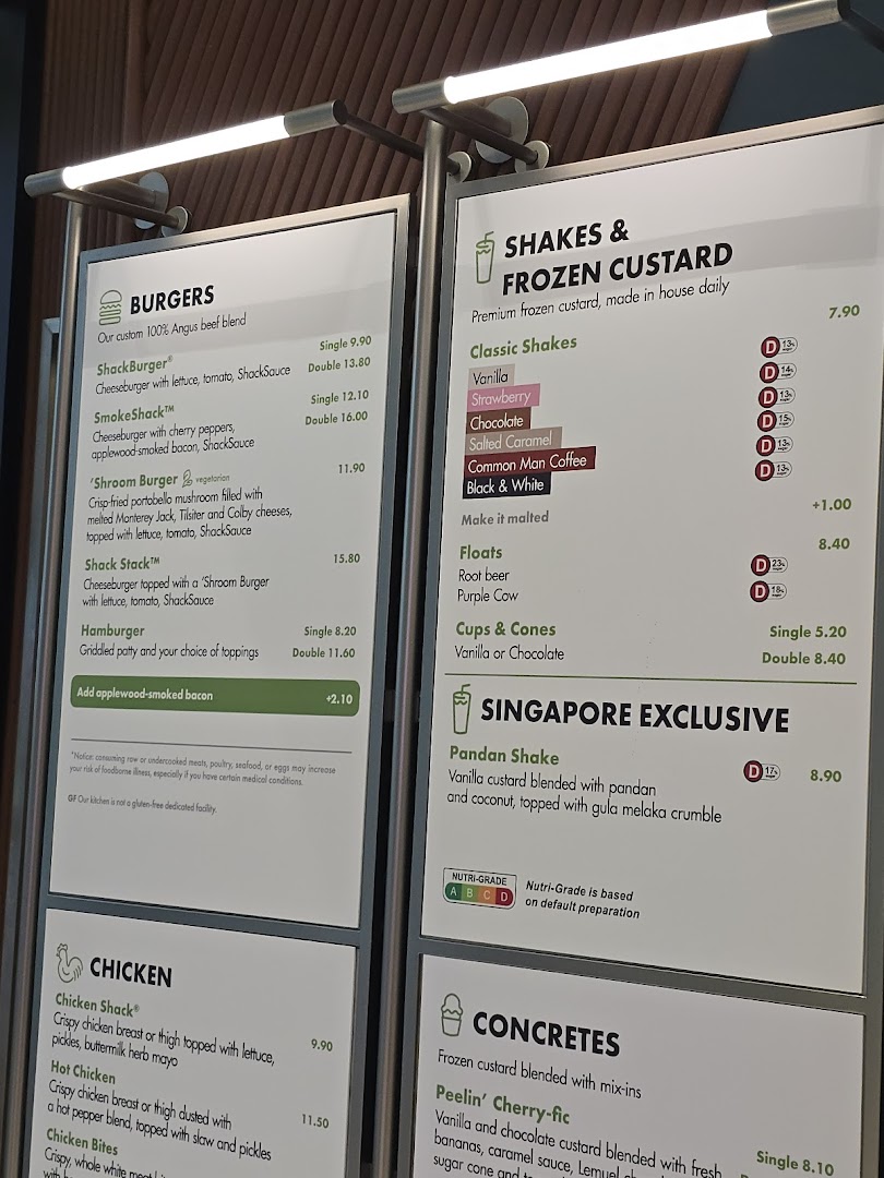 A detailed menu board displaying burgers, shakes, chicken, and concretes with prices.
