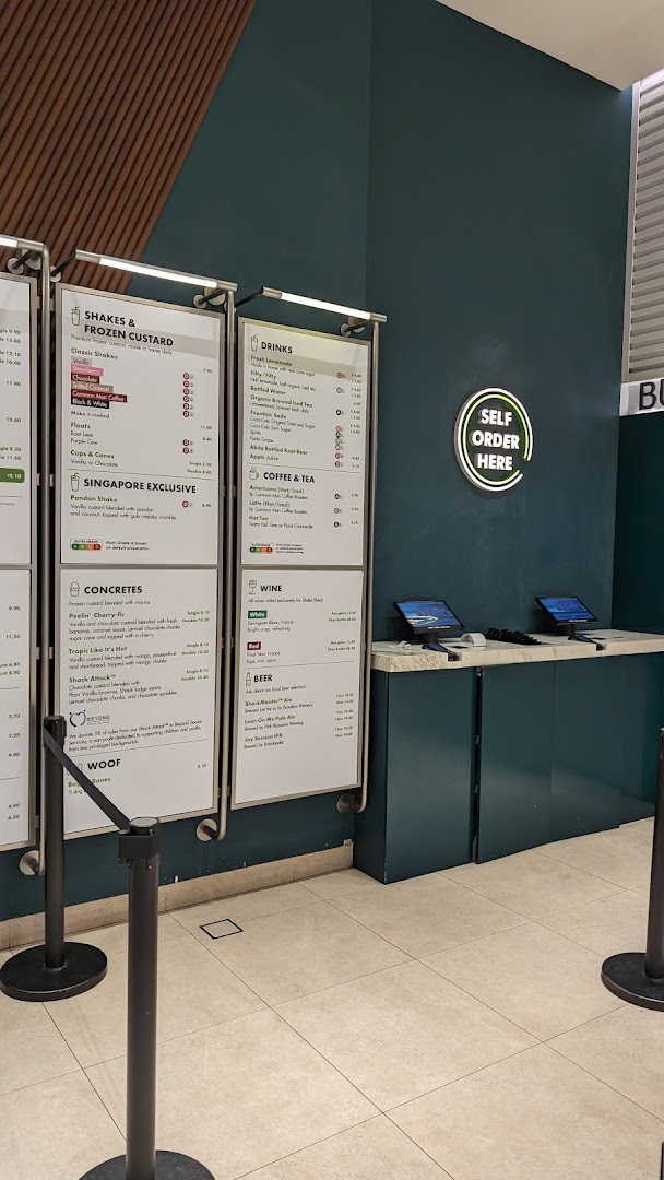 Shake Shack's menu boards displaying shakes, concretes, drinks, and self-order kiosks.