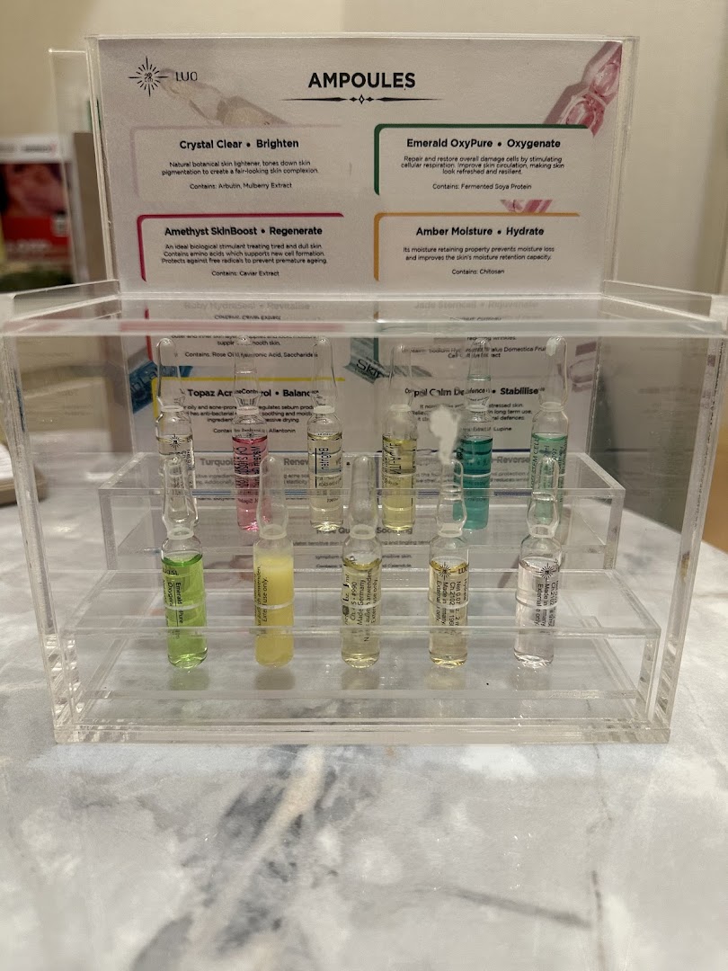 A clear display stand showcasing various skincare ampoules with their benefits and ingredients.