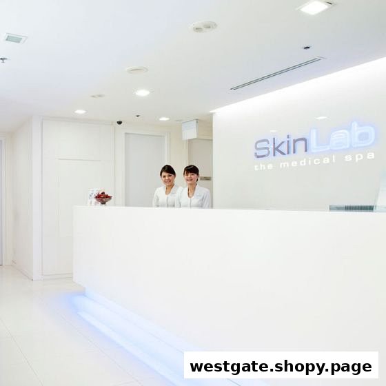 Two friendly staff members stand behind a sleek white reception desk at SkinLab The Medical Spa.
