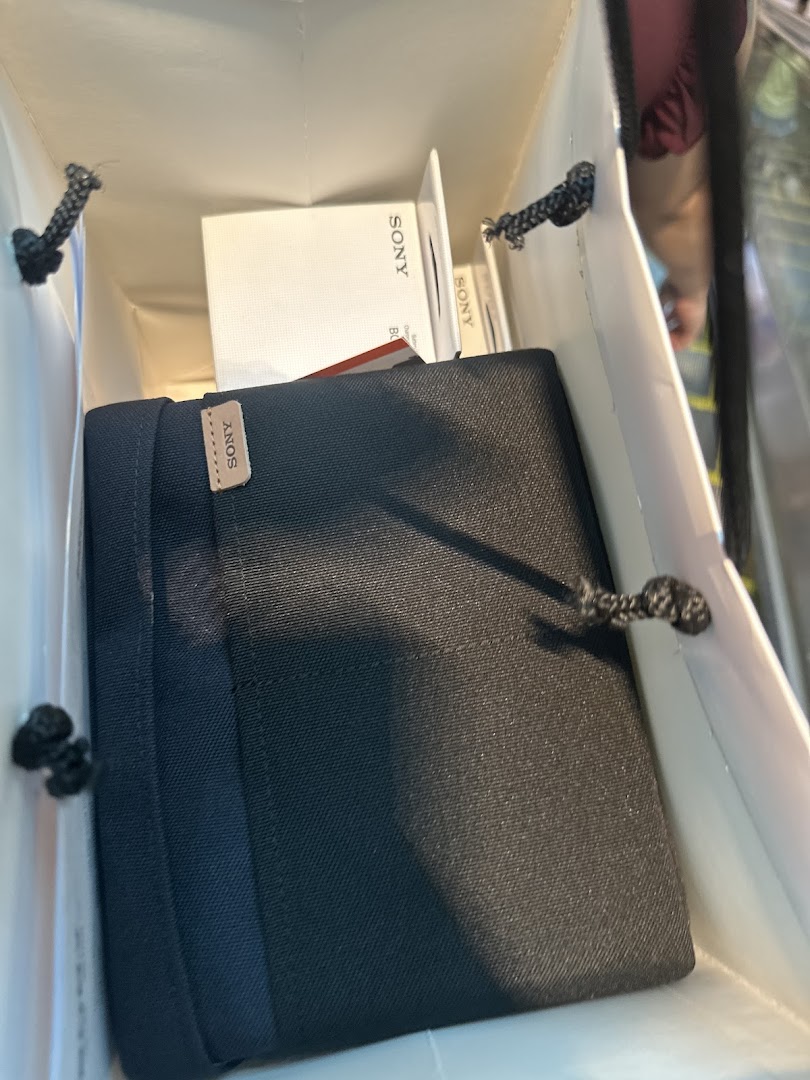 A shopping bag from Sony Store filled with newly purchased Sony products, including a black case and white boxes.