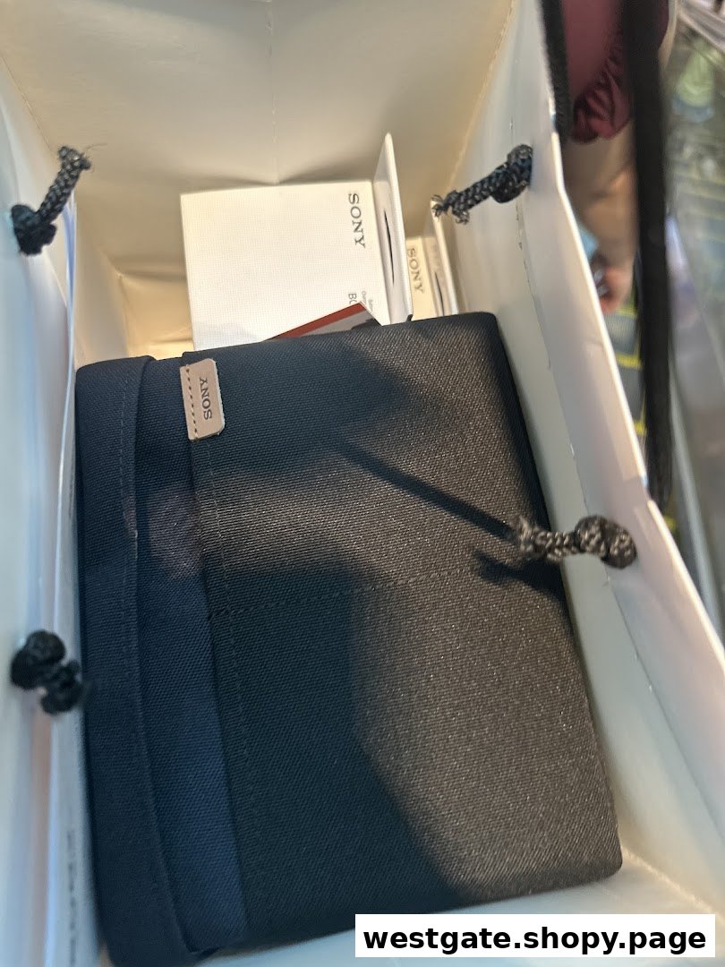 A shopping bag from Sony Store filled with newly purchased Sony products, including a black case and white boxes.