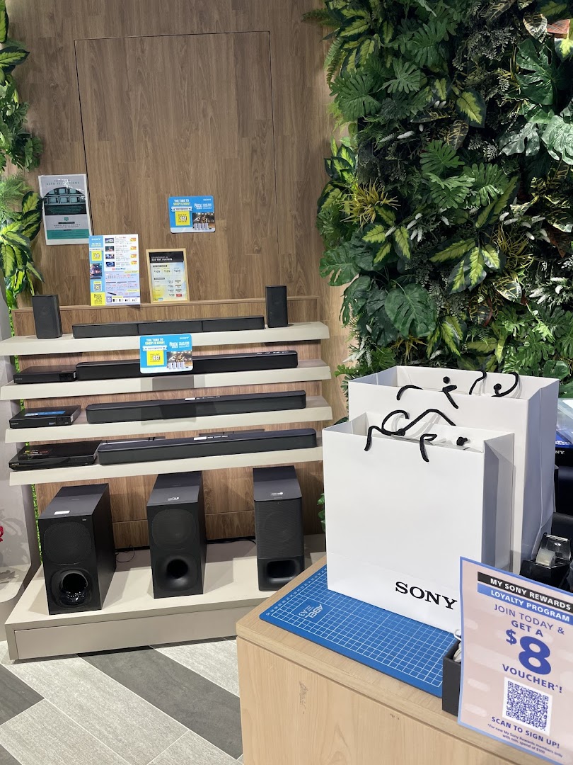 Sony soundbars and subwoofers displayed in a modern store setting with lush green wall decor.