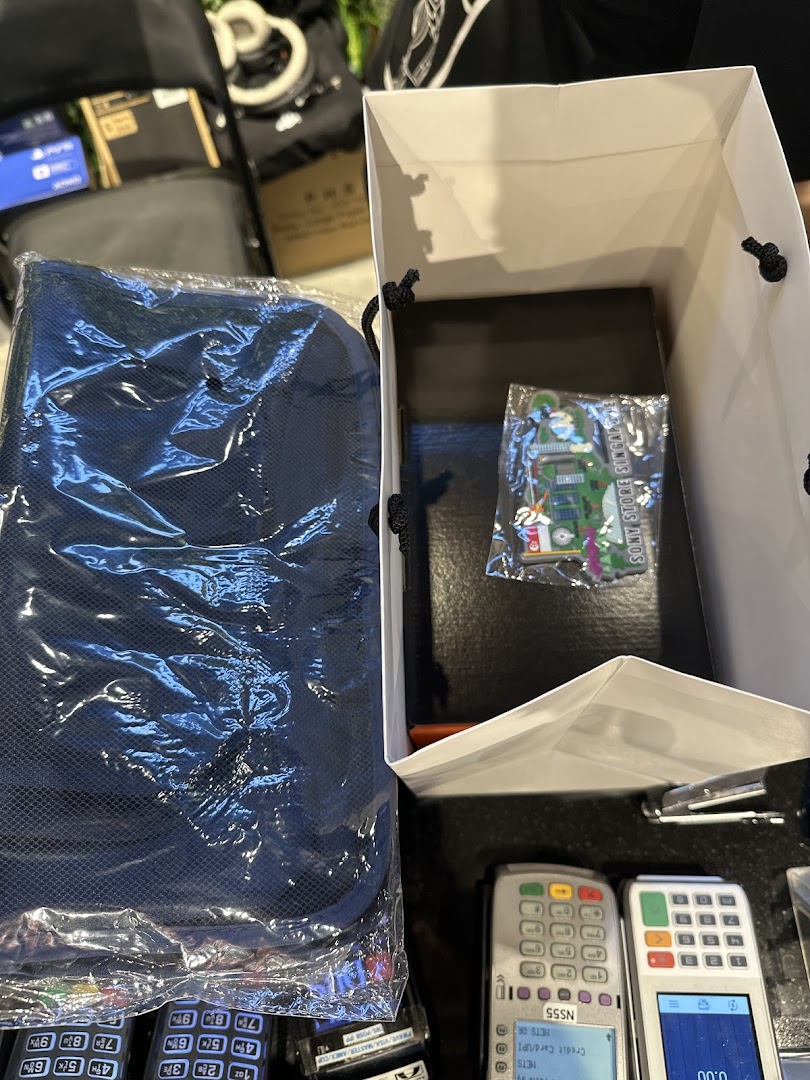 Items purchased from Sony Store, including a blue bag and a Sony Store Singapore souvenir, next to payment terminals.
