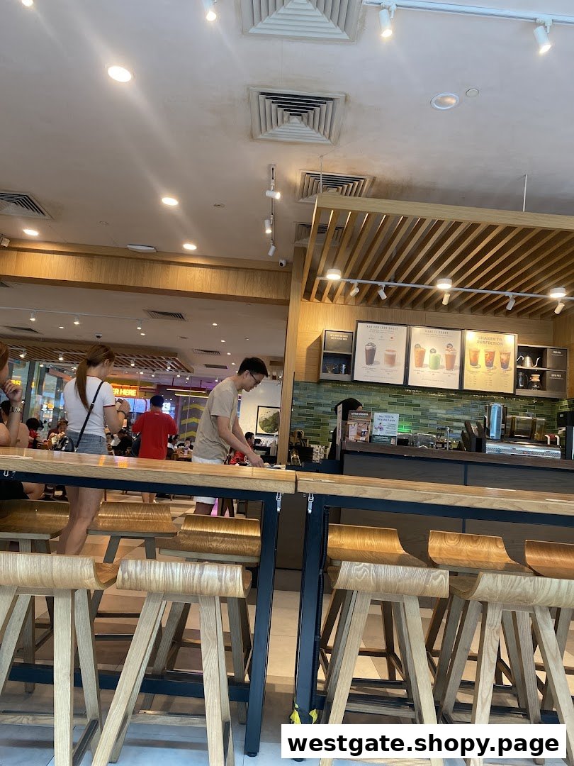 An interior view of Starbucks Westgate, showing customers, seating, and the service counter.