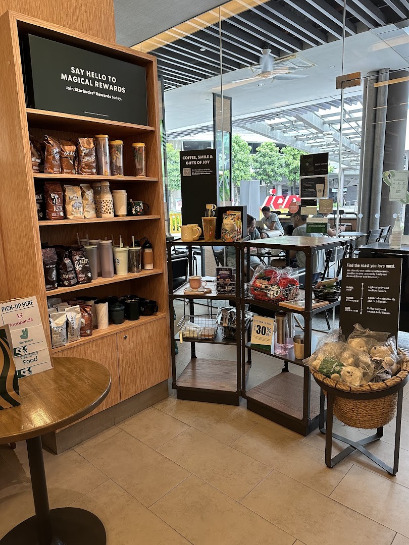 Starbucks interior featuring merchandise shelves, a seating area, and a view through large glass windows.