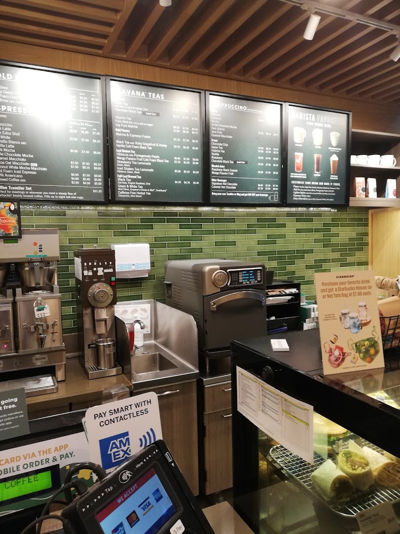 A view of the Starbucks counter area, featuring menu boards, coffee machines, and a display case.