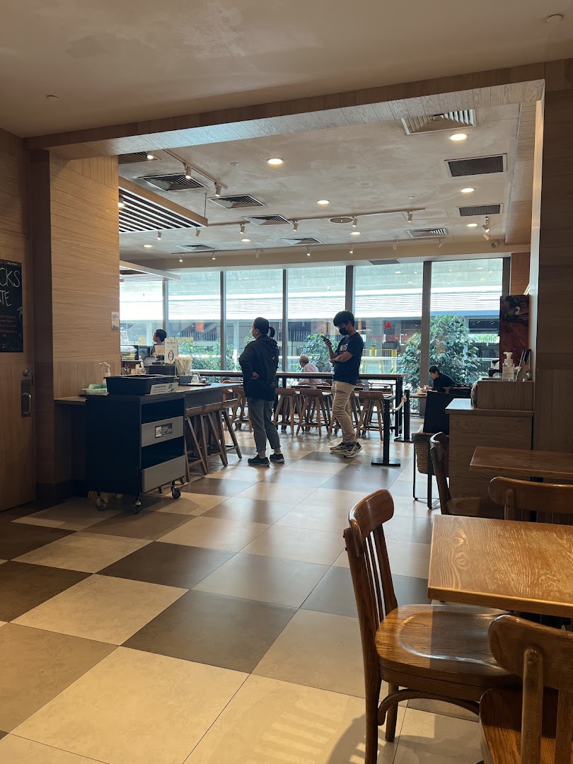 Interior view of Starbucks Westgate, showing customers, seating, and a bright window area.