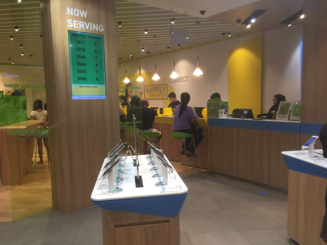 Interior view of StarHub Westgate, showing customer service counters, a queue display, and product showcases.