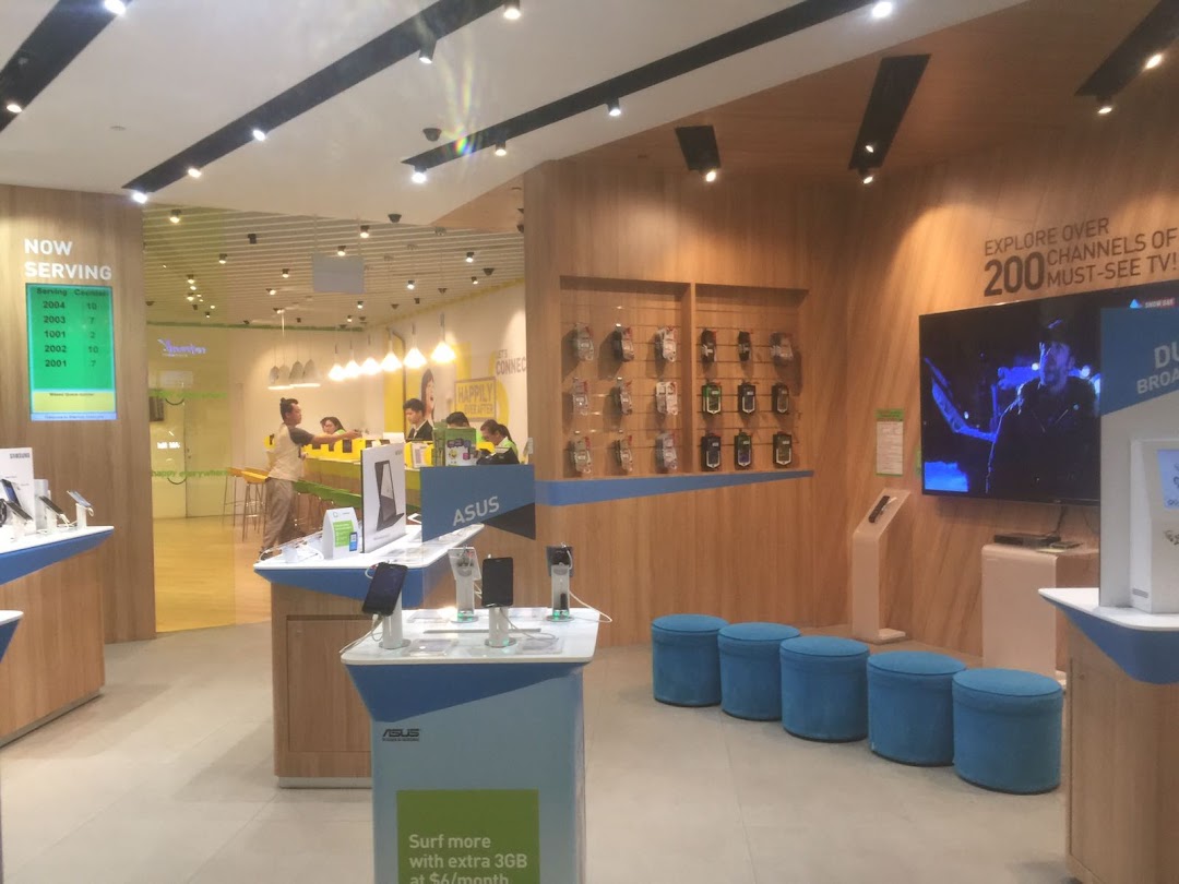 An interior view of StarHub Westgate, showcasing display counters, a service area, and a large screen.