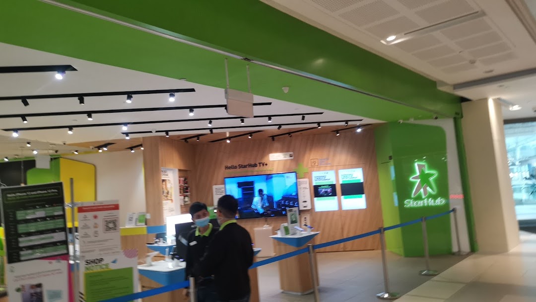 Interior view of StarHub Westgate, showcasing product displays, a large screen, and staff assisting customers.