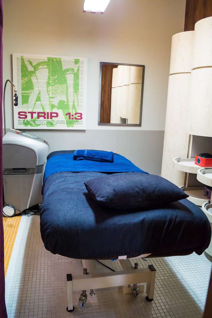 A comfortable treatment room at Strip Co-Ed Westgate, featuring a bed and specialized equipment.