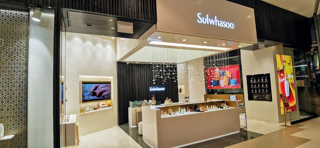 An elegant Sulwhasoo boutique interior featuring product displays, a service counter, and a staff member.