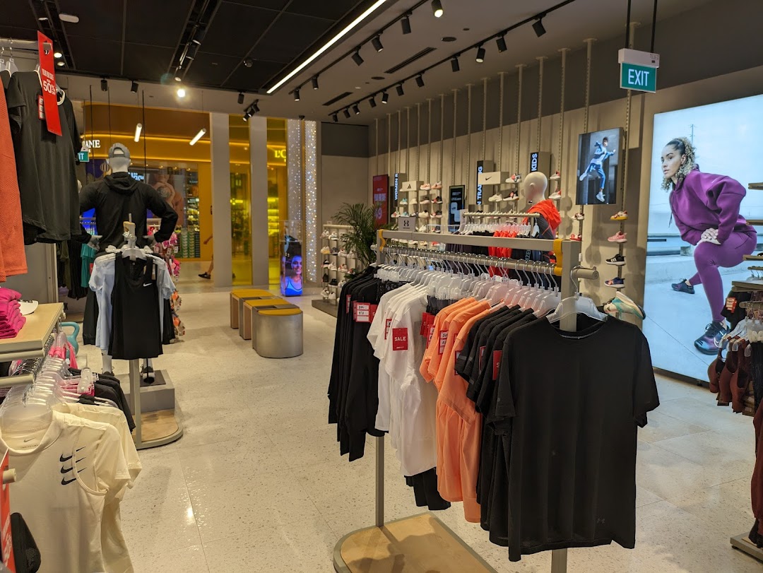 Interior view of Sun & Sand Sports, showcasing activewear, footwear displays, and mannequins in a brightly lit space.