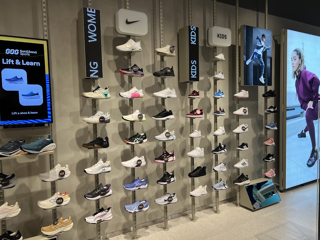 An interior shot of Sun & Sand Sports, showcasing a wide array of athletic footwear for women, men, and kids on a wall display.