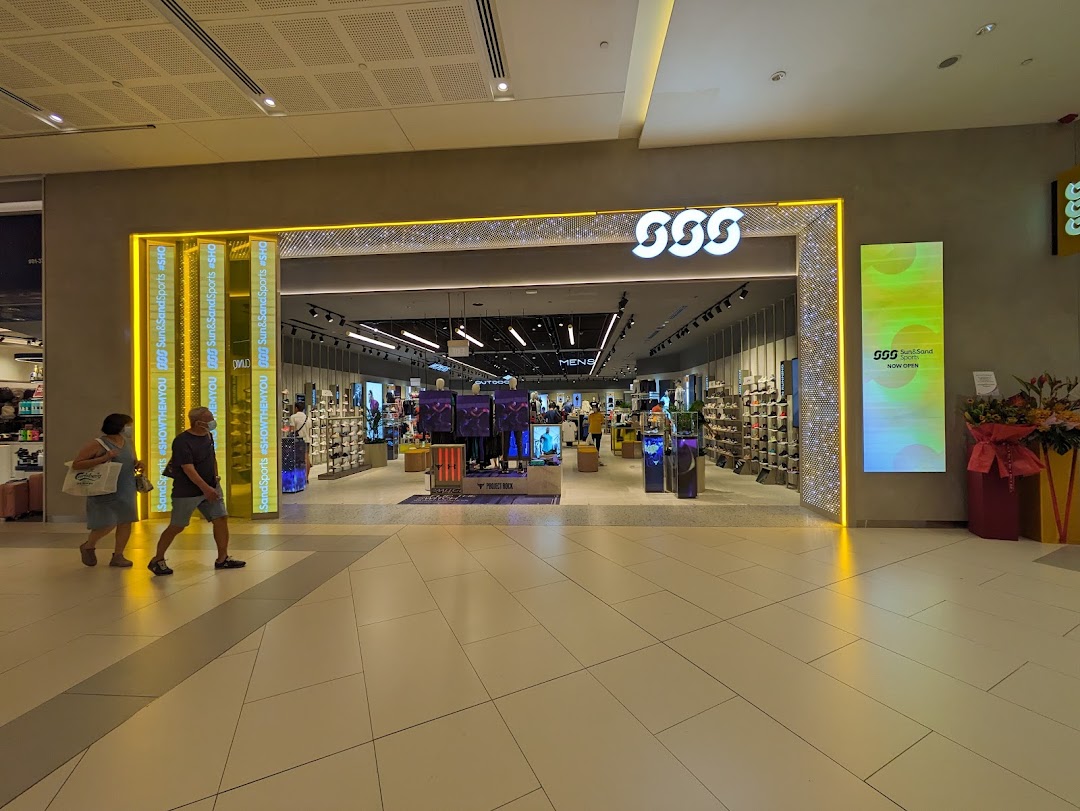 The brightly lit entrance of Sun Sand Sports, showcasing athletic footwear and apparel, with shoppers passing by.