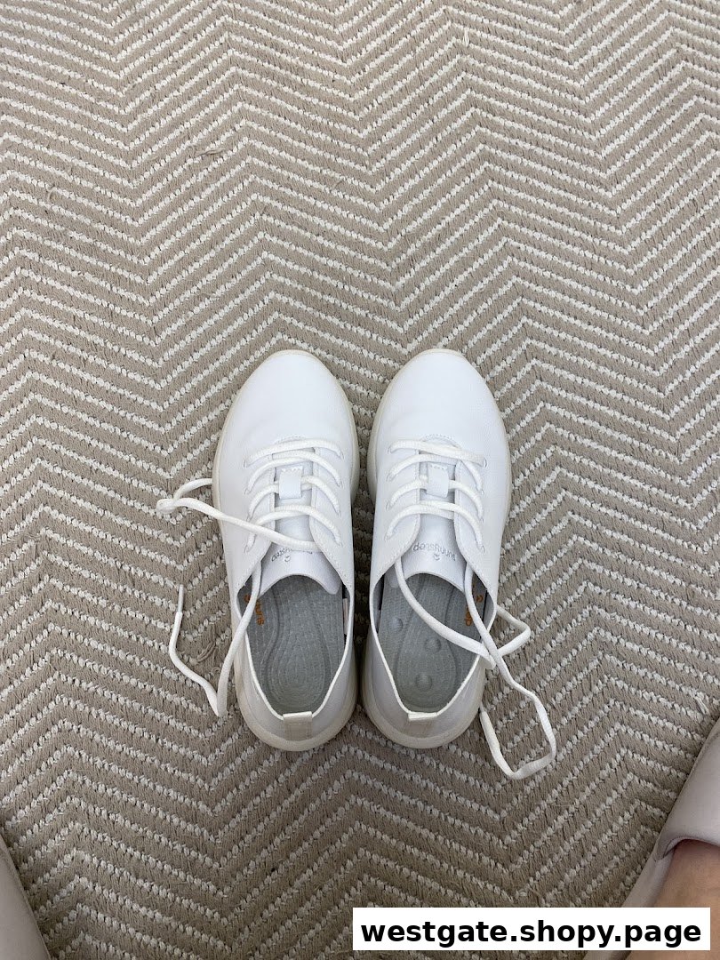 A pair of white Sunnystep sneakers on a patterned carpet, showcasing the brand's footwear.