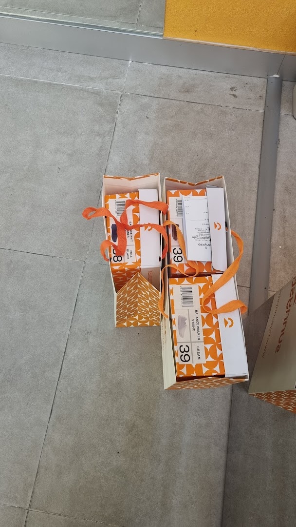 Sunnystep shoe boxes with orange ribbons and product labels on a tiled floor.