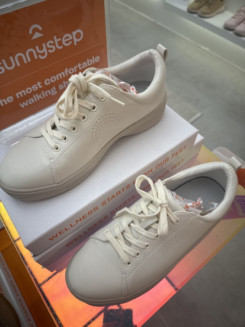 A pair of white Sunnystep sneakers displayed with branding and wellness messaging.