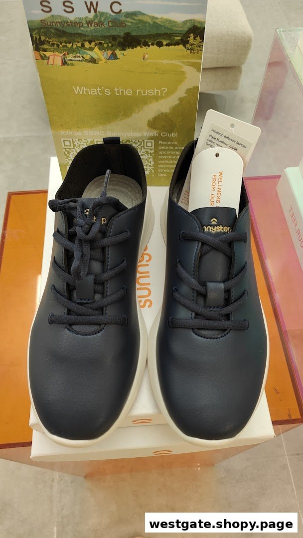 A pair of dark blue Sunnystep Balance Runner shoes displayed with a Sunnystep Walk Club promotional stand.