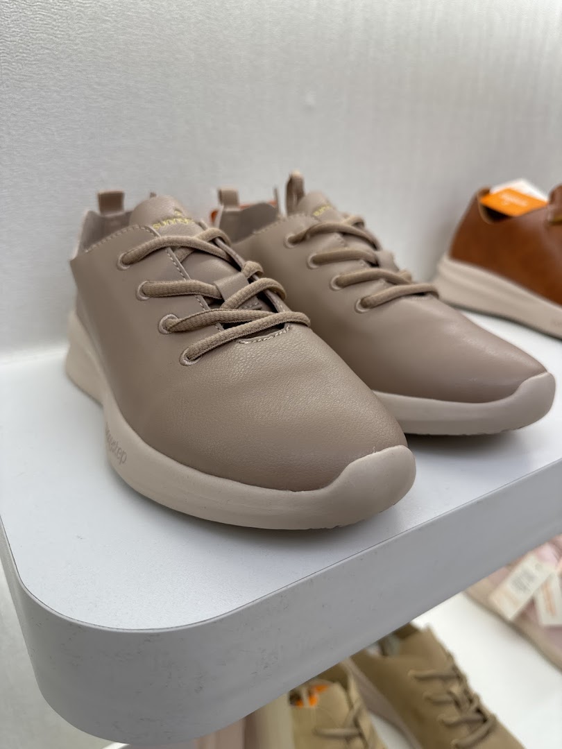 A close-up of a pair of stylish beige Sunnystep shoes displayed on a white shelf.