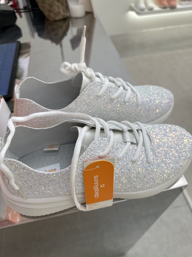 A close-up of a pair of sparkling white Sunnystep sneakers with a product tag.
