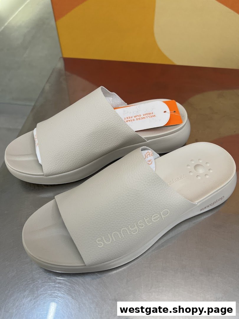 A pair of light beige Sunnystep comfort sandals displayed, featuring the brand logo and a product tag.