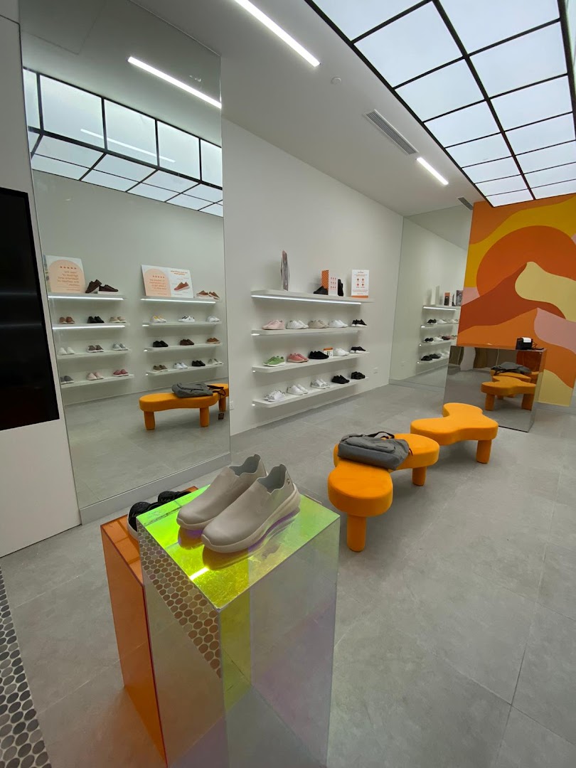 Bright, modern shoe store interior with shoes displayed on shelves and a colorful mural.