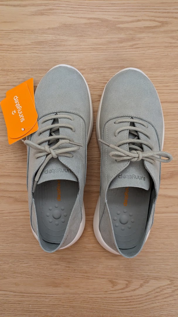 A pair of light grey Sunnystep shoes with tags displayed on a wooden surface.