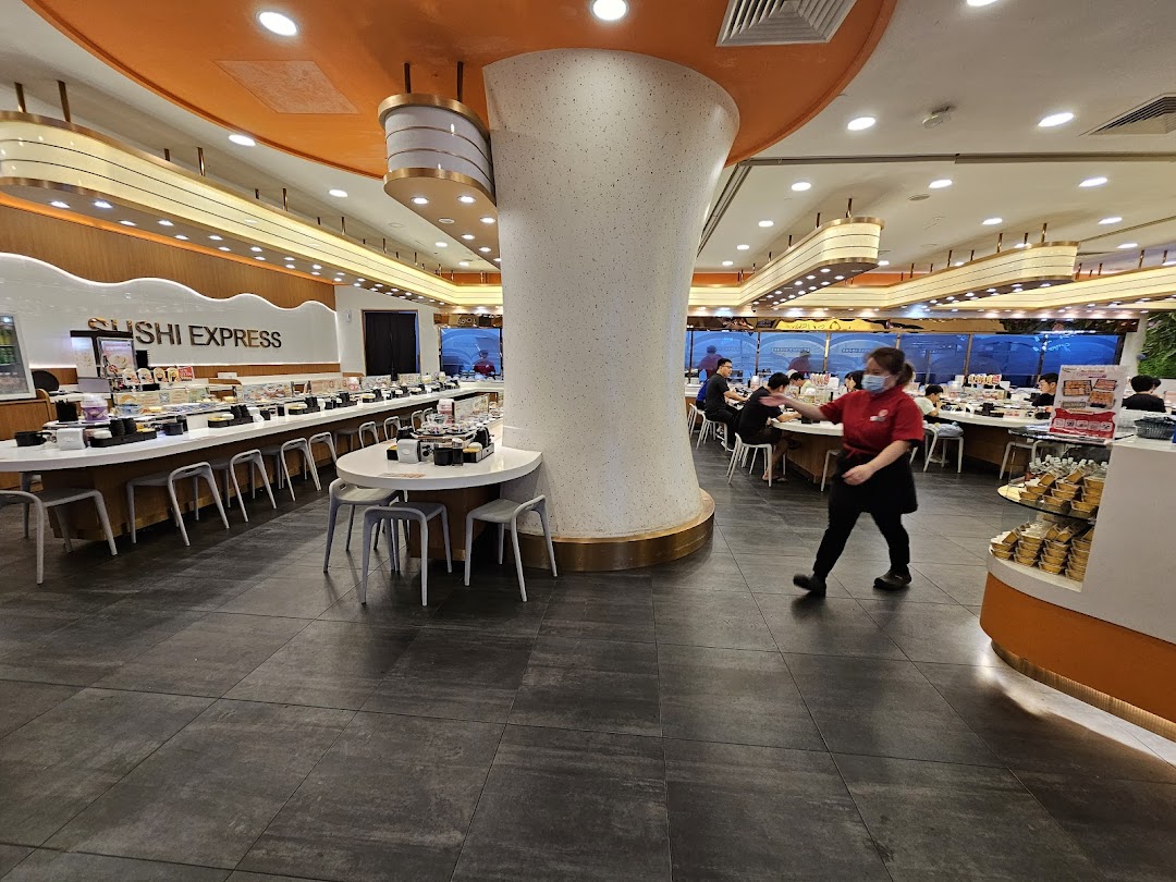 Interior view of Sushi Express, showcasing its conveyor belt sushi system and a staff member.