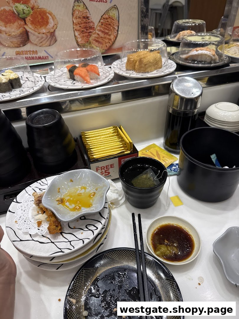 A bustling sushi conveyor belt restaurant with various sushi plates, condiments, and used dishes on the table.