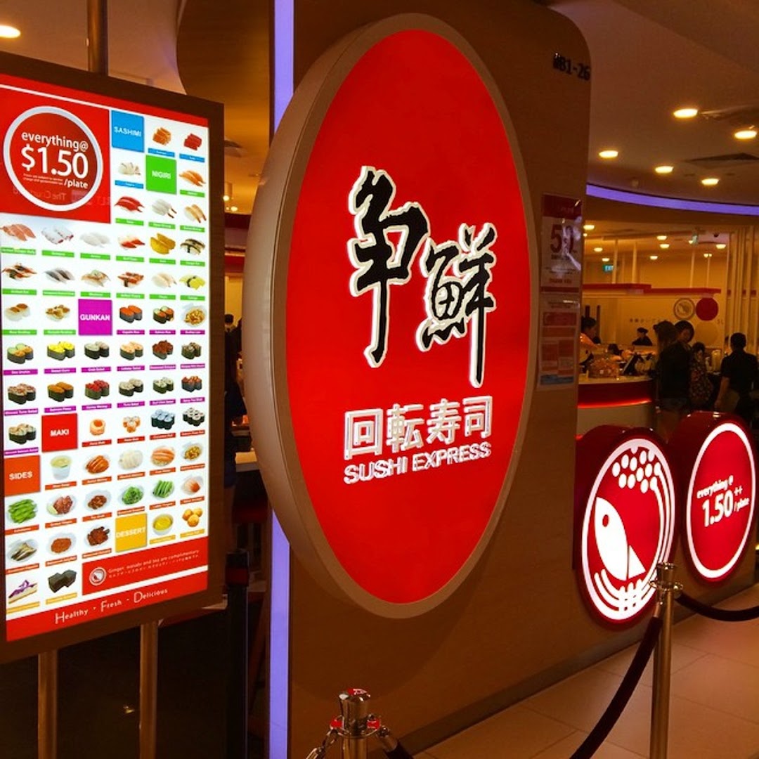 The vibrant entrance of Sushi Express, featuring a large illuminated menu board and brand signage.