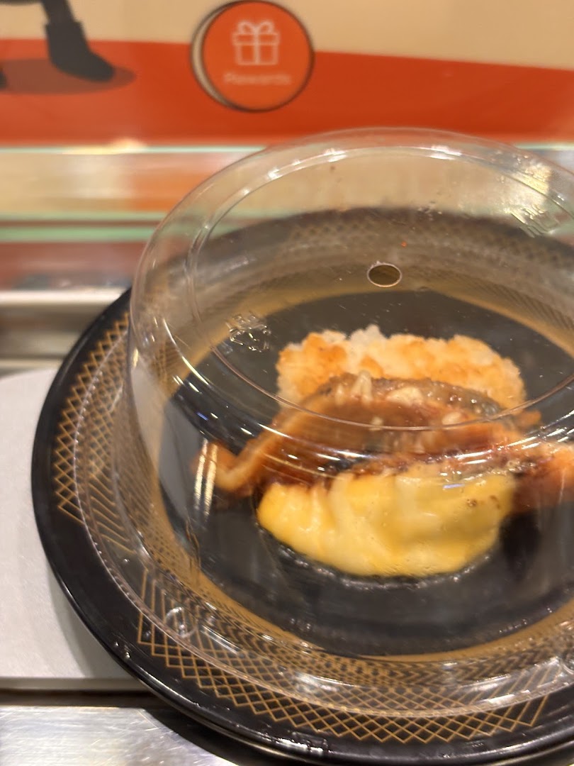 A covered sushi plate with eel and tamago on a conveyor belt at Sushi Express.