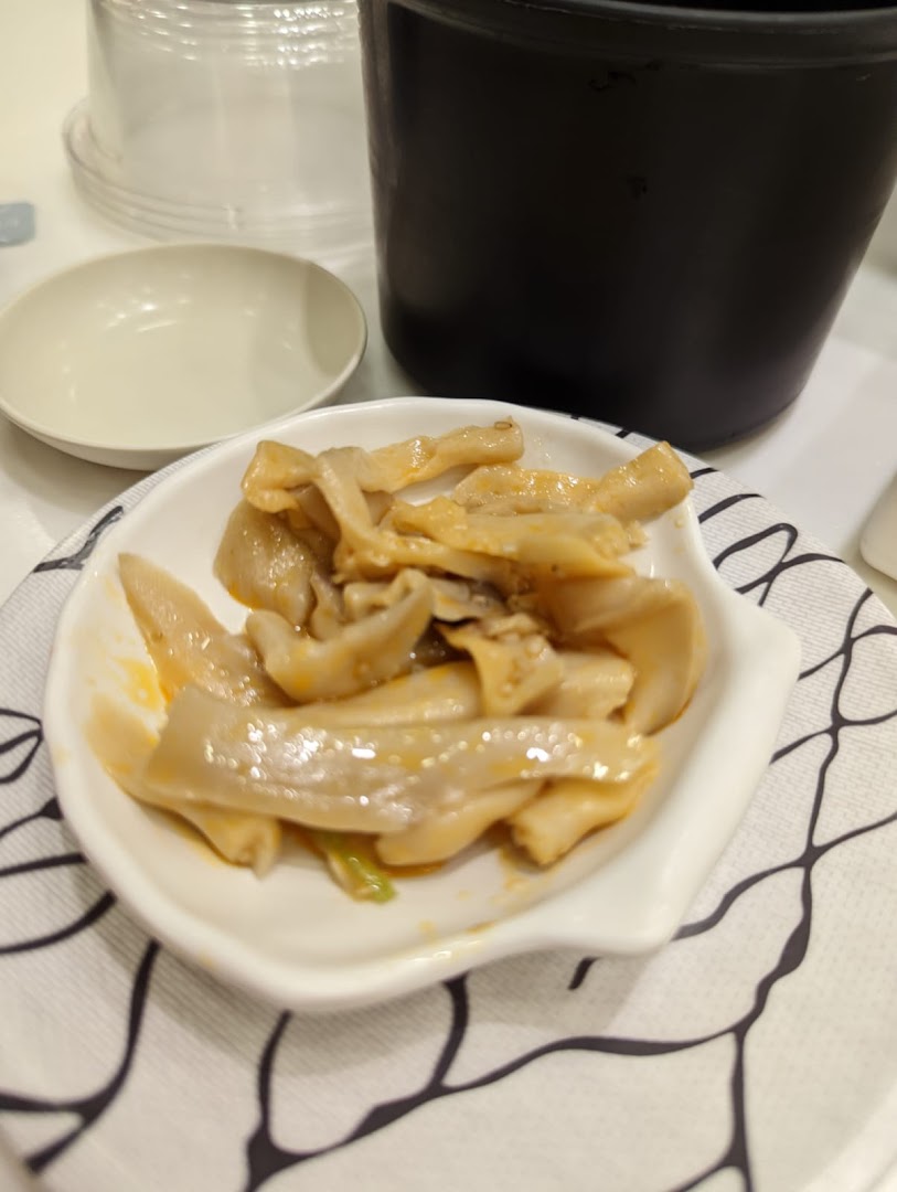 A close-up of a savory side dish, possibly marinated mushrooms or seafood, served in a white bowl.